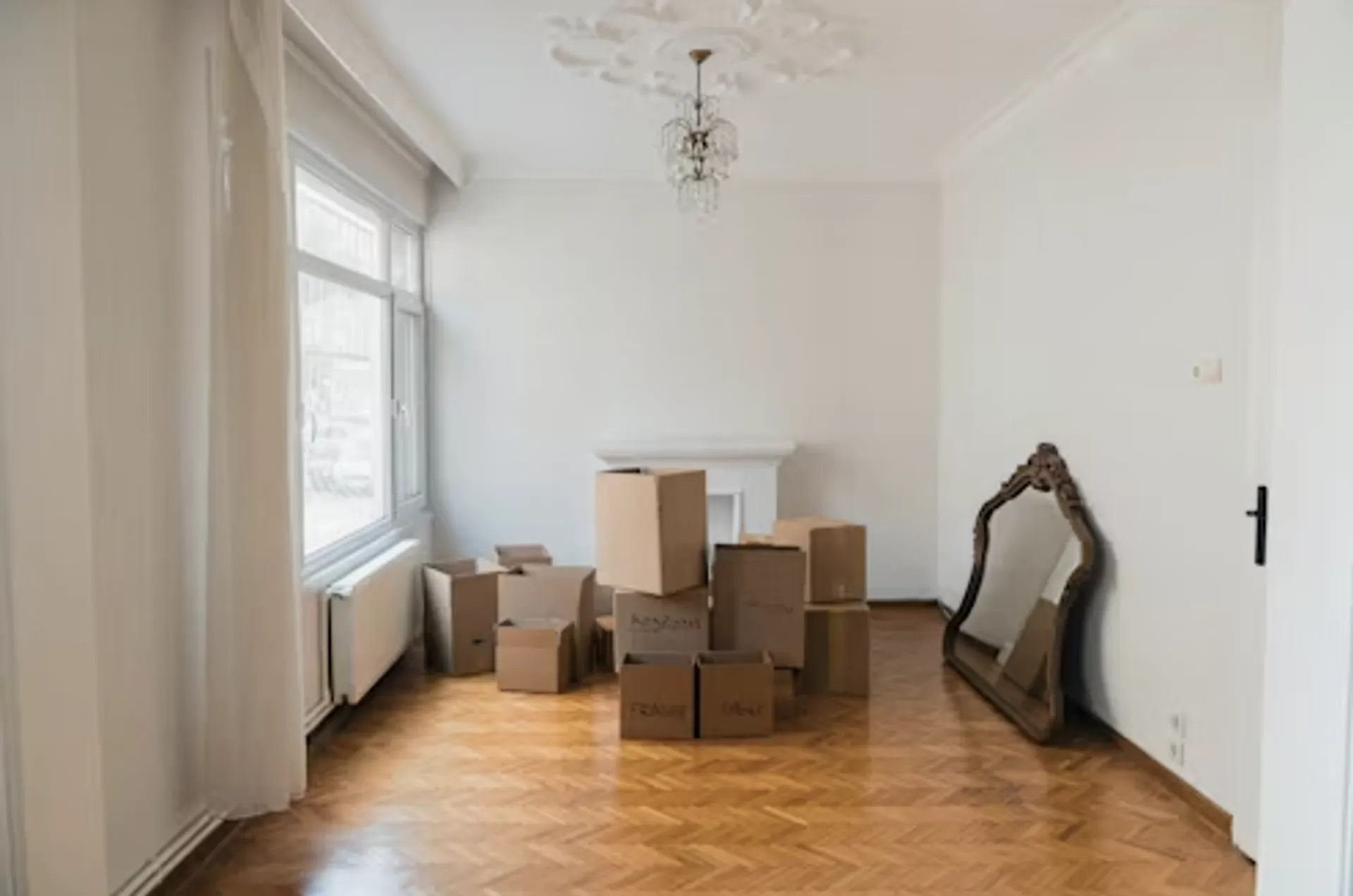 Wohnzimmer mit Umzugskartons auf dem Boden und Spiegel an der Wand, Kamin verdeckt